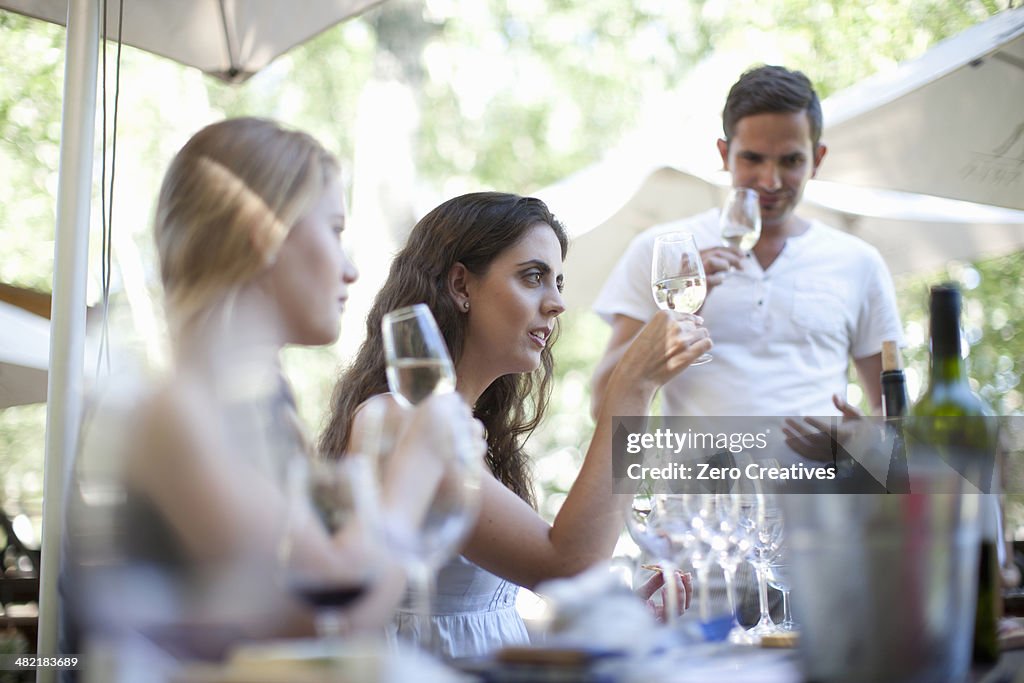 Young friends tasting and looking at wine at vineyard bar