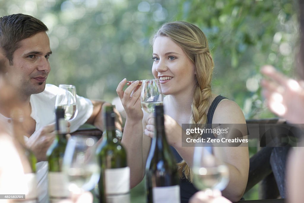 Young friends tasting and smelling wine at vineyard bar