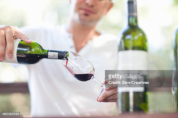 young male waiter pouring red wine at vineyard bar - bar drink establishment stock pictures, royalty-free photos & images