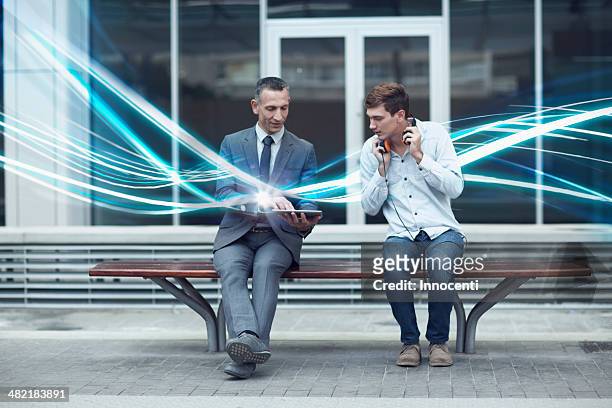businessman and young man watching digital tablet and waves of illumination - light discovery stock-fotos und bilder