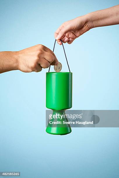 studio shot of hand putting coin into charity collection box - money donation stock-fotos und bilder