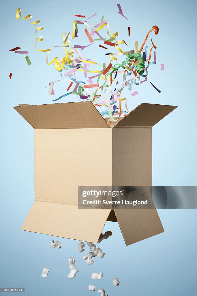 Studio shot of cardboard box with streamers exploding out