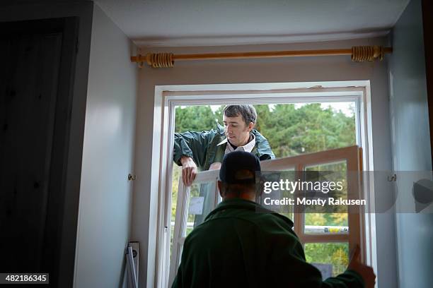 father and son builders installing new window in house - substitution photos et images de collection