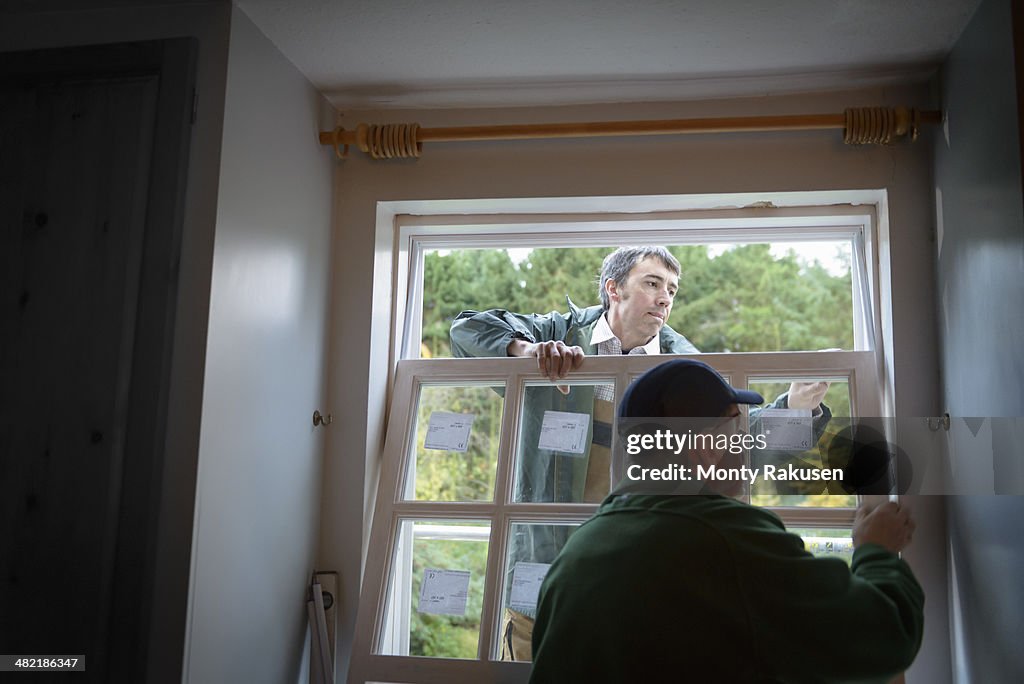 Father and son builders installing new window in house