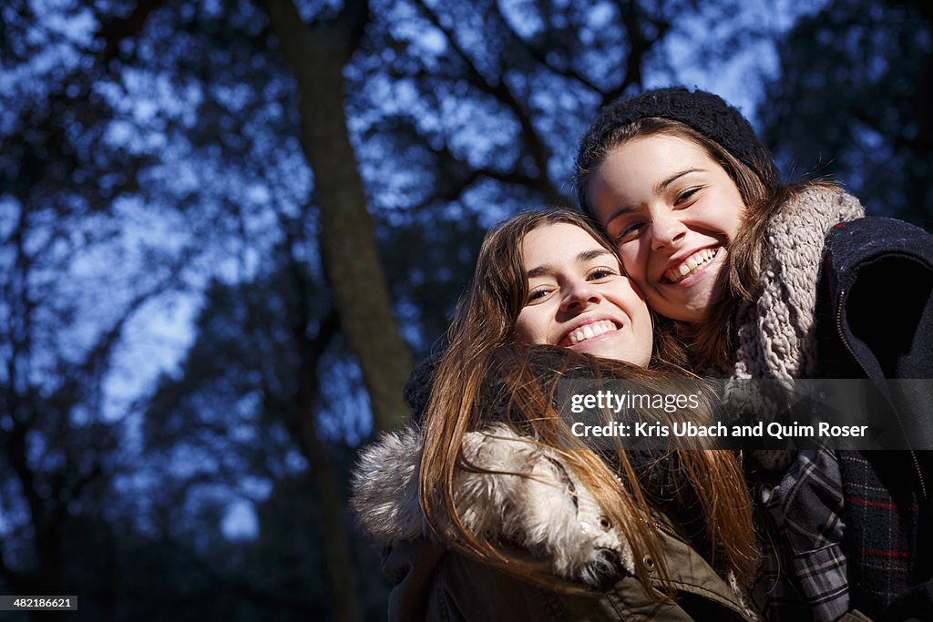 Sisters hugging in forest at dusk
