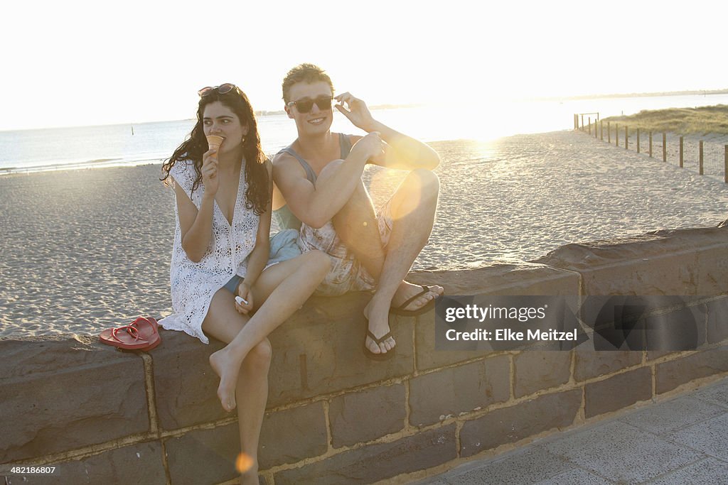 Young couple sitting on wall, Port Melbourne, Melbourne, Australia