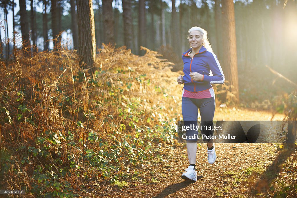 Mature woman jogging on forest path