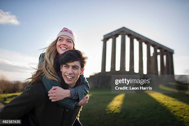 a young couple on calton hill with the background of the national monument of scotland in edinburgh - edinburgh scotland stock-fotos und bilder