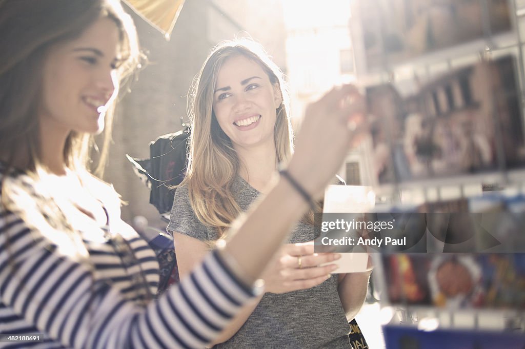 Two young female friends looking at postcards, Valencia, Spain