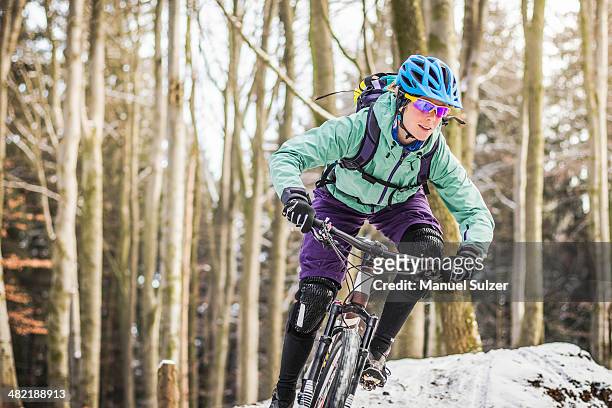 female mountain biker riding through forest - athleticism stockfoto's en -beelden