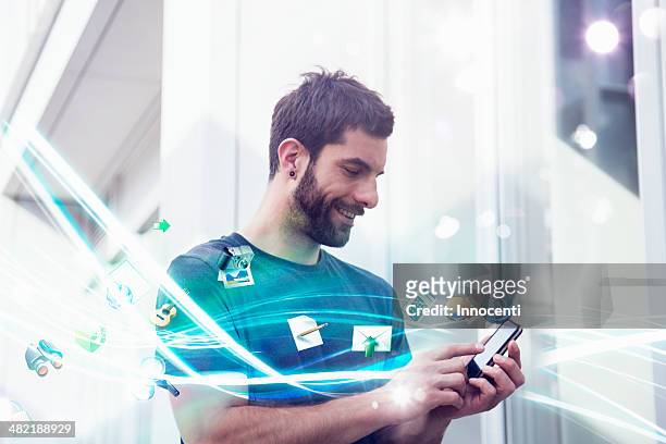 mid adult man with apps and lights coming from smartphone - bandwidth stock-fotos und bilder