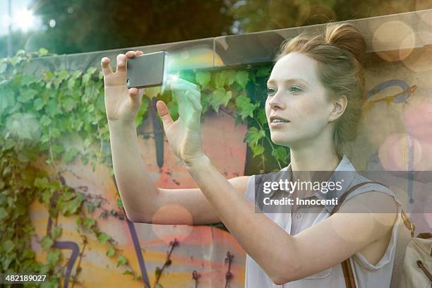 young woman photographing self on illuminated smartphone - photographing graffiti stock pictures, royalty-free photos & images