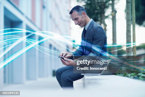 Waves of blue light and businessman texting on smartphone Waves of blue light and businessman texting on smartphone