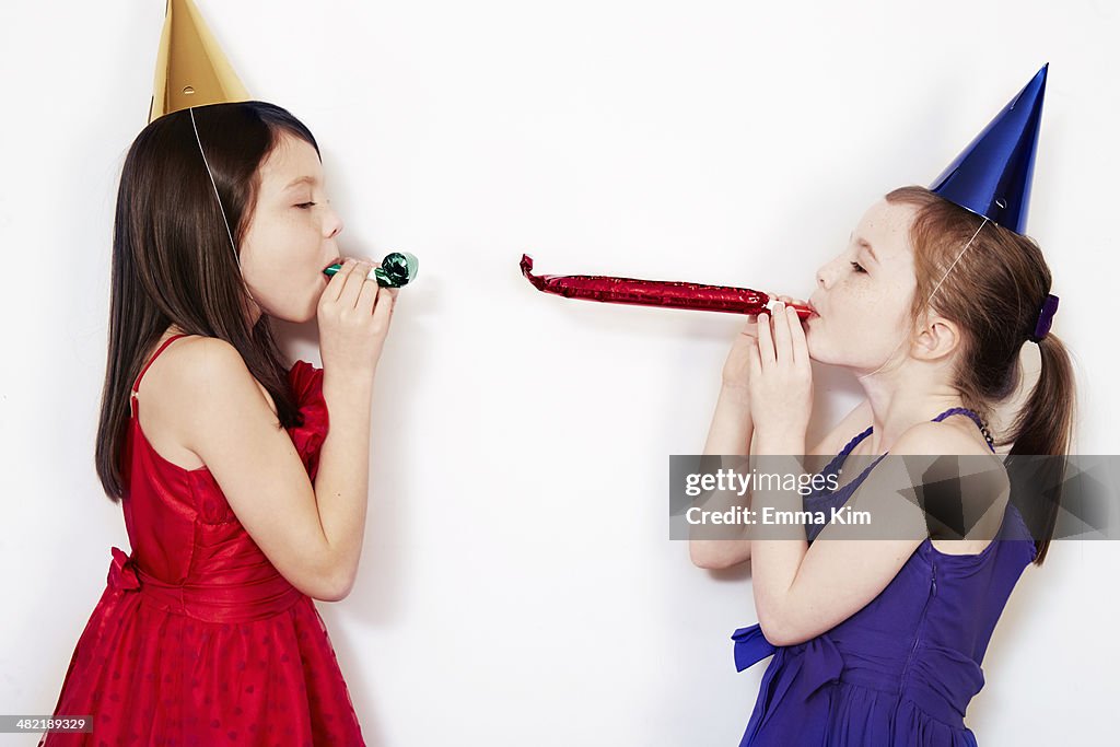 Portrait of two girls blowing party blowers