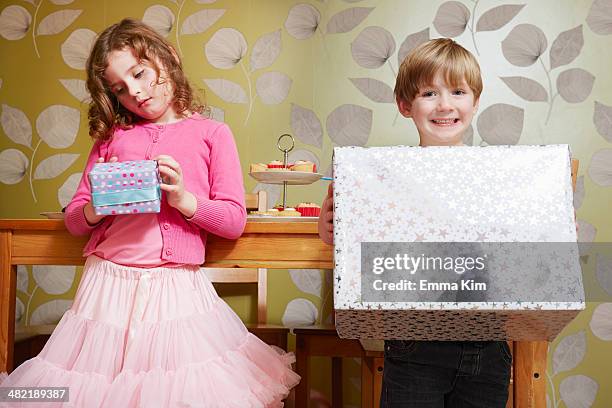 boy and girl holding large and small present - small gift box stock pictures, royalty-free photos & images