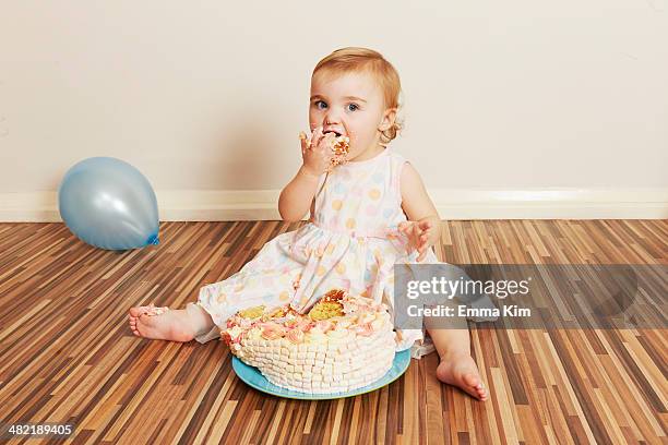 toddler girl devouring birthday cake - lampoon first birthday event stock-fotos und bilder