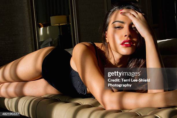 portrait of sultry young woman reclining on bedroom seat - mujer seductora fotografías e imágenes de stock