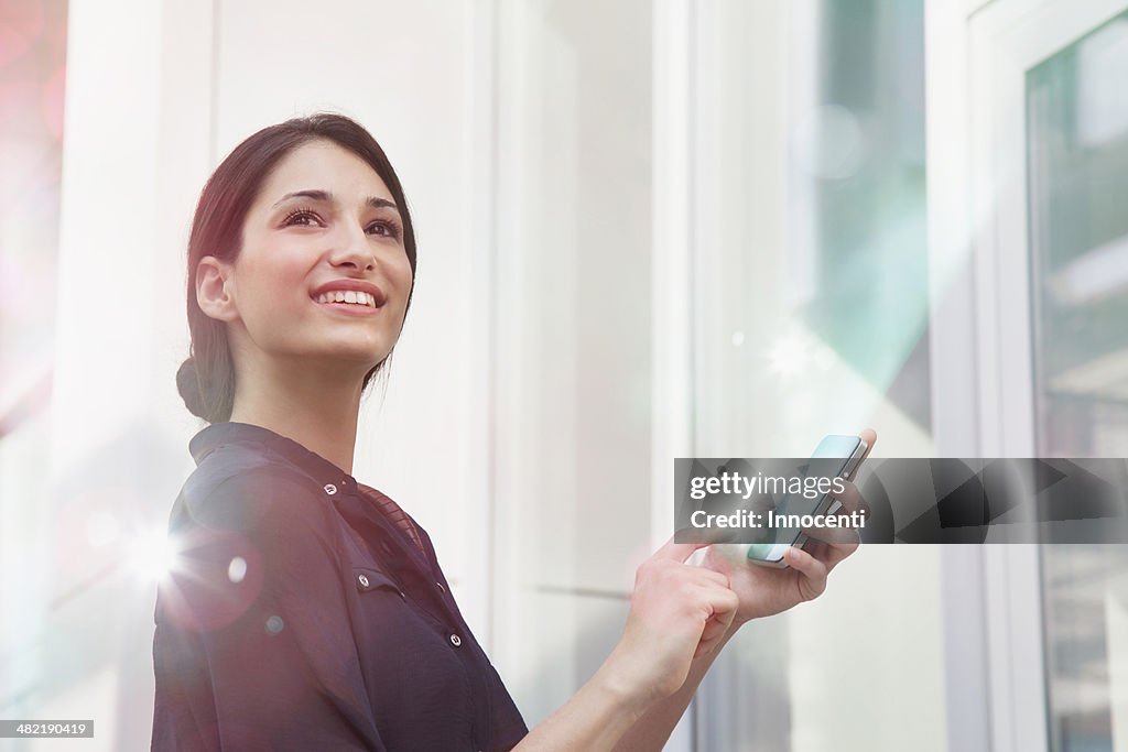 Young businesswoman holding smartphone with lights coming out of it