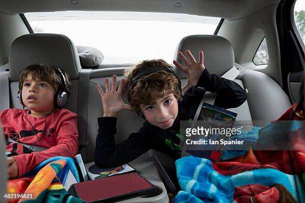 brothers in back seat of car, wearing headphones - kid listening stock pictures, royalty-free photos & images