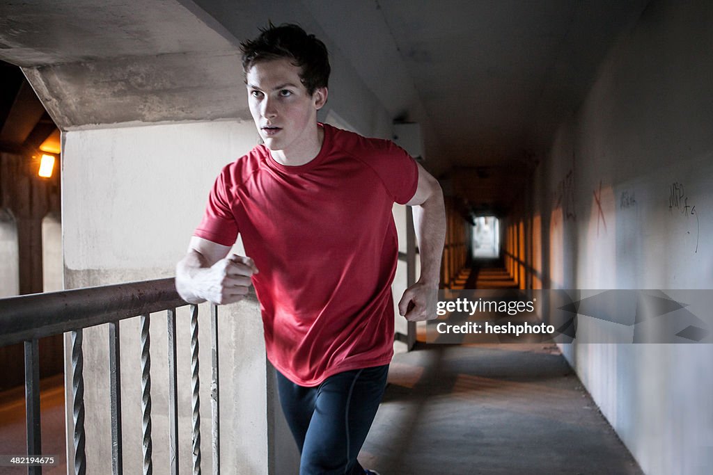 Young man running on city bridge