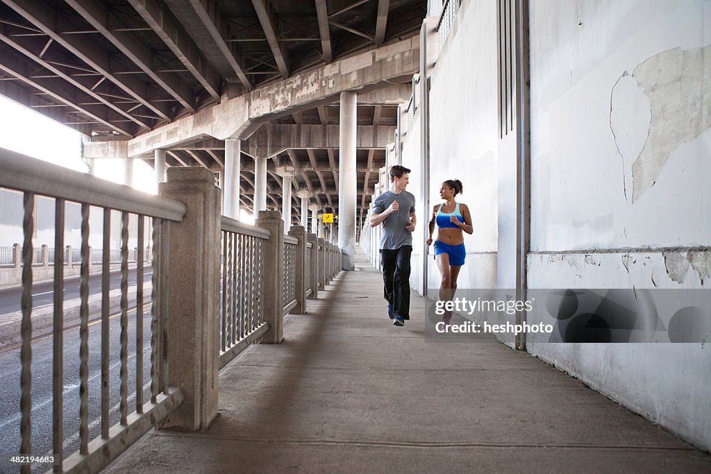 Young couple running on city bridge