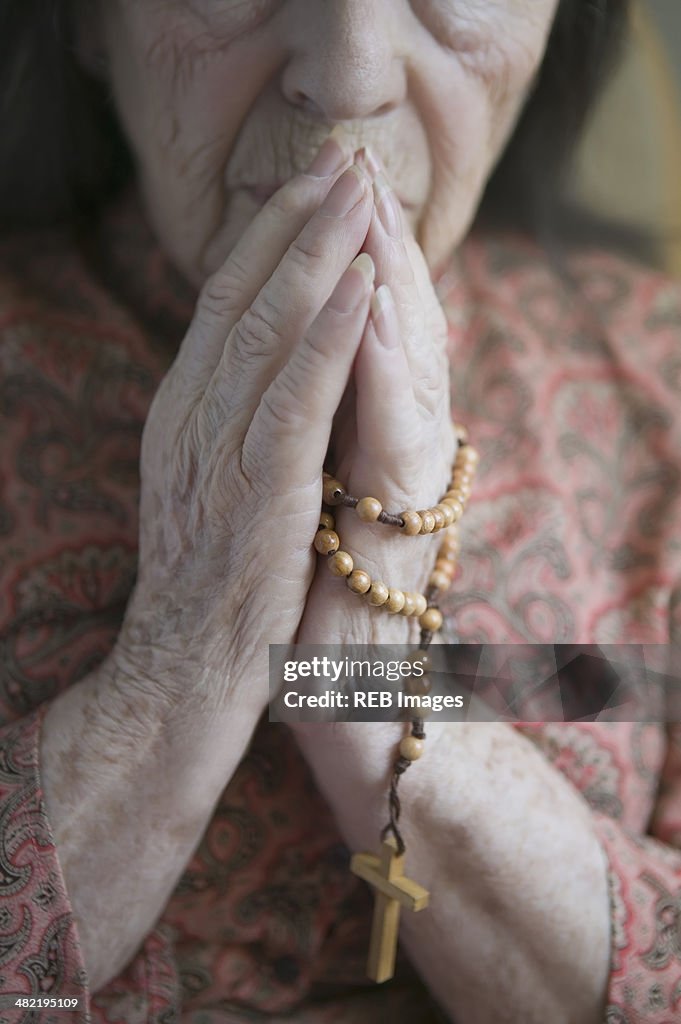 Senior woman praying with rosary