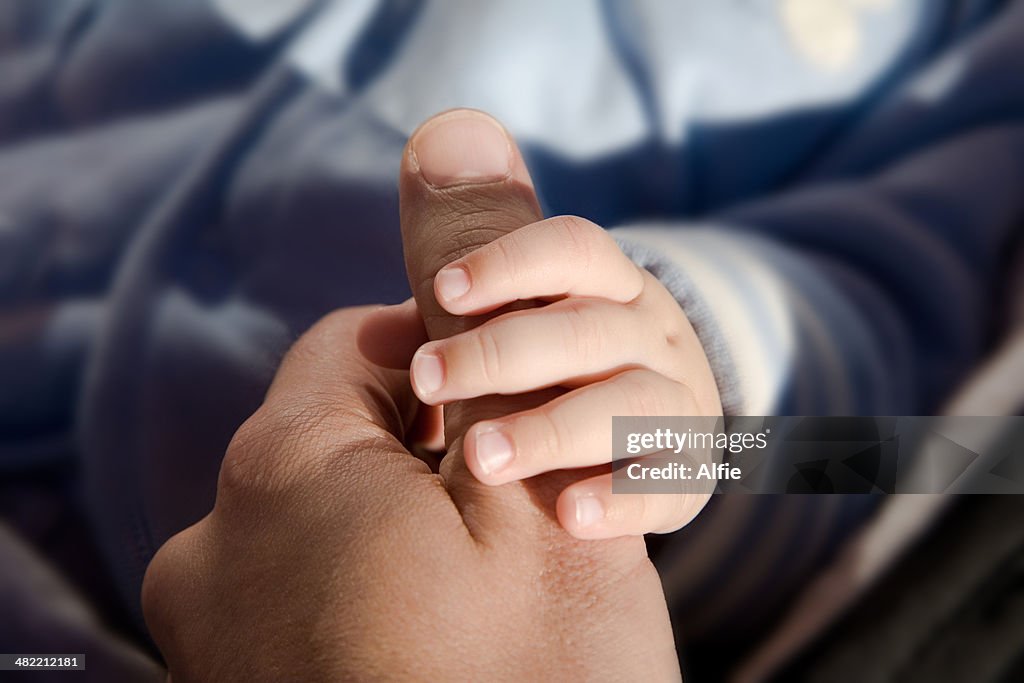Bebê segurando a mão da