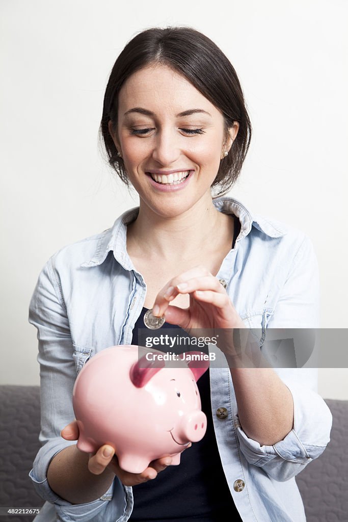 Young Woman putting coin in piggy bank
