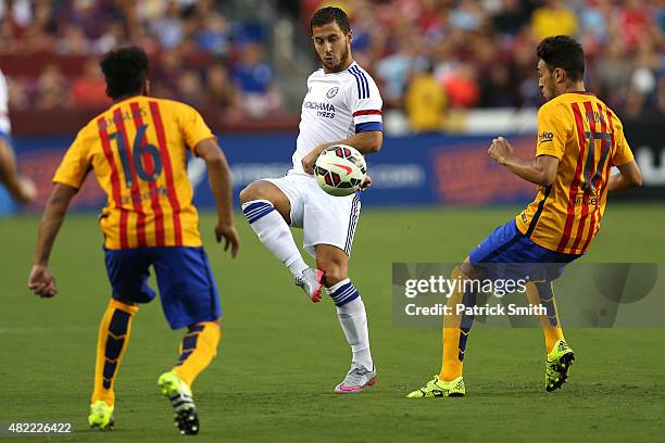 Eden Hazard of Chelsea passes between two Barcelona defenders in the first half during the International Champions Cup North America at FedExField on...