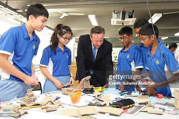 British Prime Minister, David Cameron engages with students during a Design & Technology lesson for a class of Lower Secondary School at the...