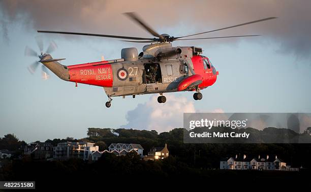 Royal Navy Sea King helicopter from 771 Squadron based at Royal Naval Air Station Culdrose assists a woman in her 50's who is being airlifted to...