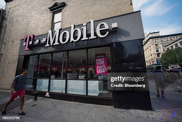 Pedestrian walks past a T-Mobile US Inc. Store in New York, U.S., on Sunday, July 26, 2015. T-Mobile US Inc. Is scheduled to release earnings figures...