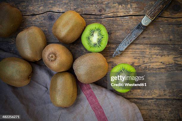 kiwis (actinidia deliciosa) and pocketknife on wooden table - kiwi fruit stock pictures, royalty-free photos & images