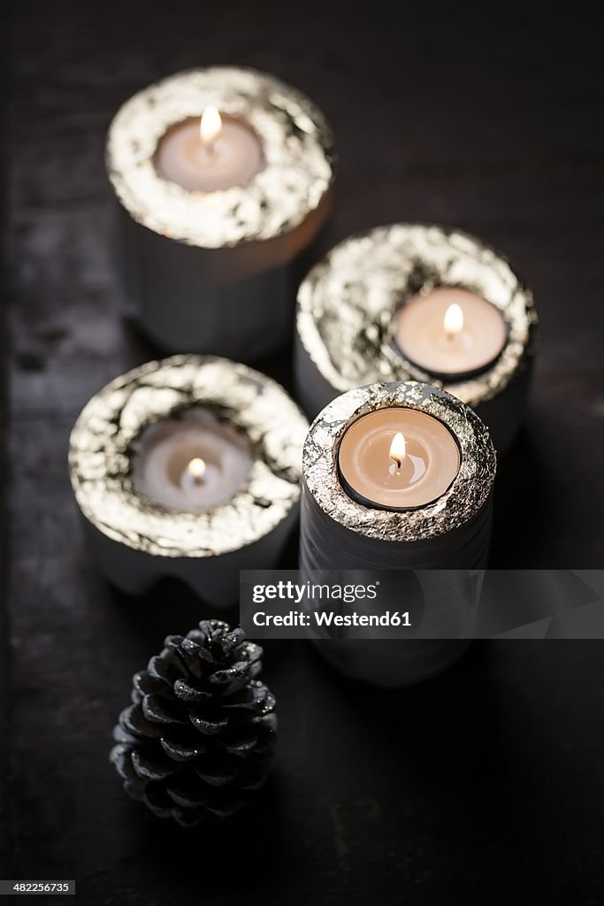 Four lighted advent candles and a fir cone