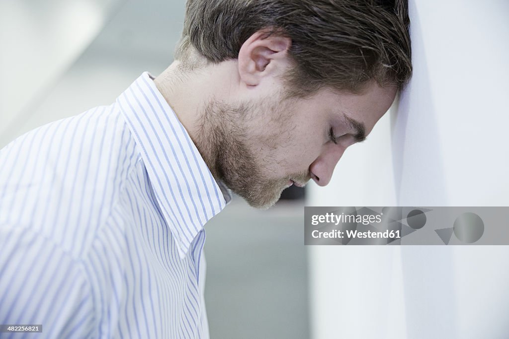 Germany, Neuss, Business man leaning head to wall