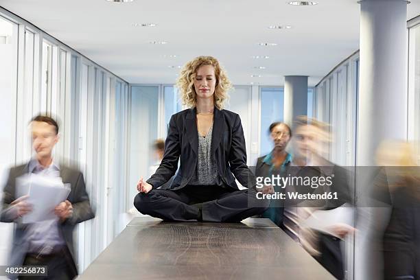 germany, neuss, business woman meditating on desk - meditation concentration stock pictures, royalty-free photos & images