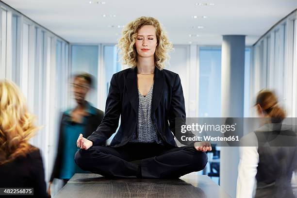 germany, neuss, business woman meditating on desk - escaping office stock pictures, royalty-free photos & images