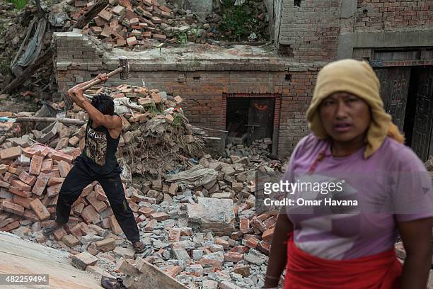Man uses a hammer to break down reinforced concrete from a collapsed building on July 29, 2015 in Bhaktapur, Nepal. Three months after the earthquake...