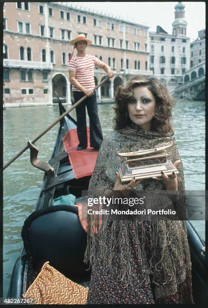 Italian singer Mia Martini on a gondola holding the Gondola d'Oro prize won at the Mostra Internazionale di Musica Leggera with the song Donna Sola....