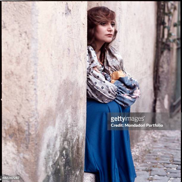 Italian singer Mia Martini sitting on a step with her arms crossed. 1973