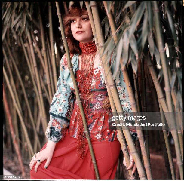 Italian singer Mia Martini sitting next to some ditch reeds. 1973
