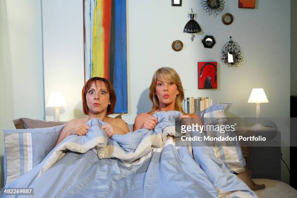 Actresses Alessia Marcuzzi and Debora Villa, both half-dressed, pose under the blanket during a photo shoot on the set of Vous les femmes in 2008 at...