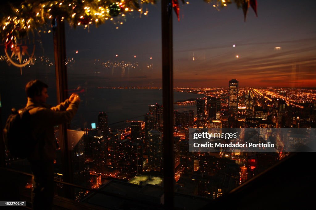 A young man takes a picture from the window on the top floor of a skyscraper