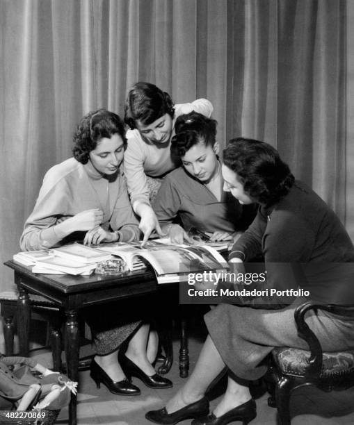 Three girls reading a magazine together. 1950s