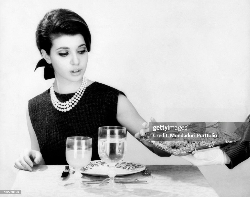 A waiter offering food on a tray to Mala Rubinstein