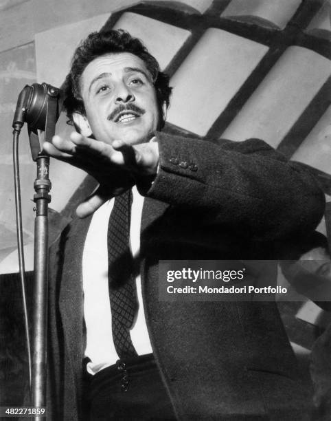 Italian singer-songwriter Domenico Modugno singing on the microphone. 1959