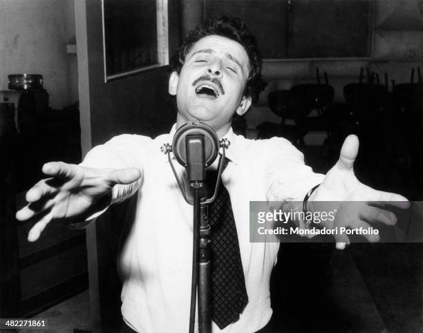 Italian singer-songwriter Domenico Modugno singing on the microphone. 1959