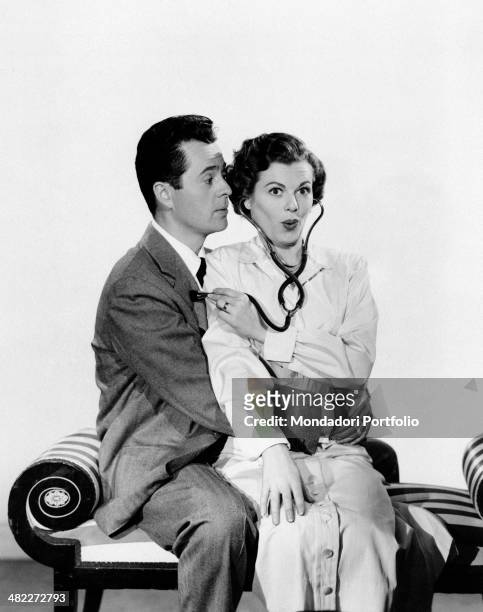 American actress Barbara Hale pretending to use a stethoscope on American actor Larry Parks' chest in the film Emergency Wedding. 1950