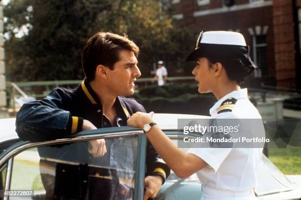 American actress Demi Moore , wearing a navy uniform, talking near a car with American actor Tom Cruise in the film A Few Good Men. 1992