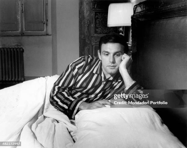 Thoughtful man in a striped pyjamas sitting in his double bed. Italy, 1960s